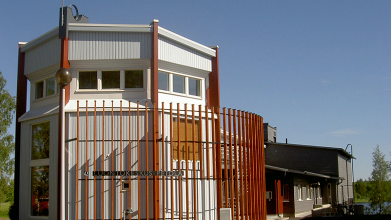 A tall and angular building with a sign on the wall identifying it as Visitor Centre Petola.